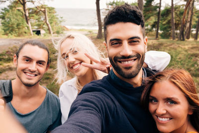 Happy male and female friends taking selfie in forest