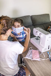 Woman making face masks with a sewing machine at home