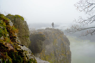 Man standing on rock against sky