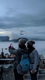 The rear view of the couple stood behind the beautiful mount bromo with the clouds gathered