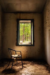 Empty chair by window in abandoned room