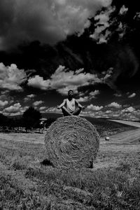 Full length of man with hay bales on field against sky