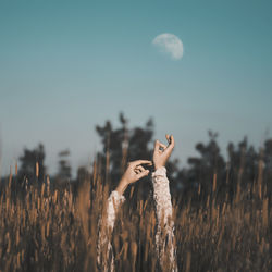Young woman standing on field against sky