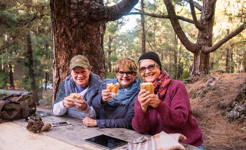 Portrait of senior women with friend having food at forest