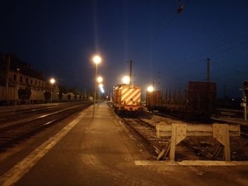 Train on illuminated street in city at night