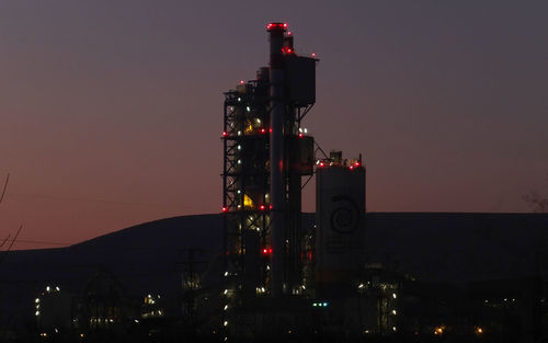 Illuminated factory against sky at night