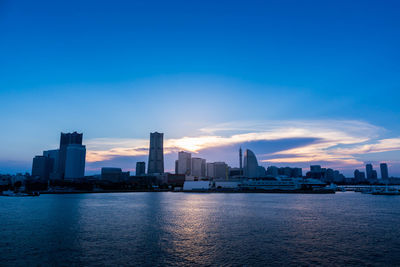 Sea by buildings against blue sky