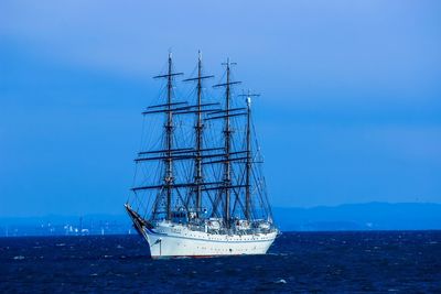 Sailboat sailing in sea against blue sky