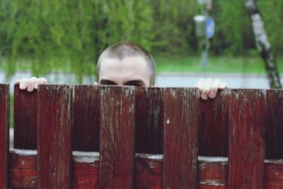 Man standing by fence against trees