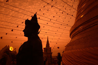 Buddha statue at temple against sky during sunset