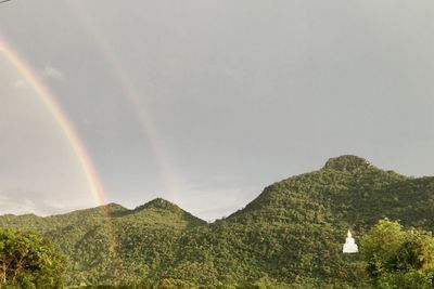 Scenic view of rainbow over landscape against sky
