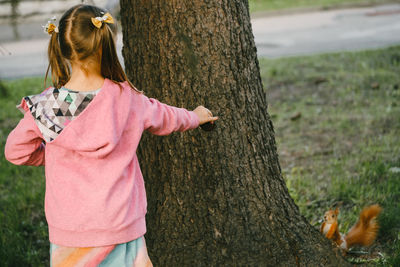 Young woman standing by tree trunk