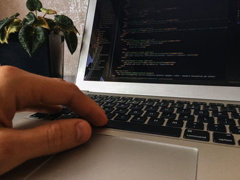 Close-up of hand using laptop on table