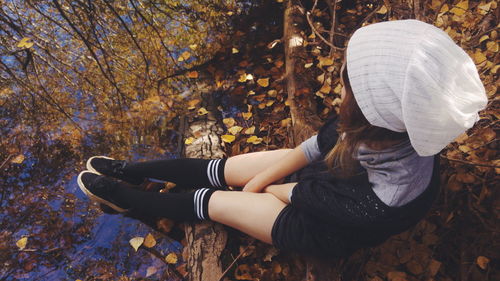 Woman sitting at lakeshore during autumn