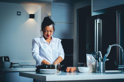 Young woman standing by glass table