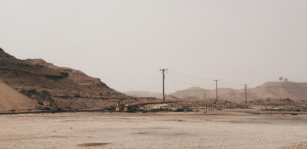 Electricity pylon on desert against clear sky