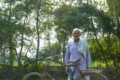 Portrait of smiling man riding bicycle on plants