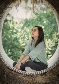 Portrait of young woman standing against trees