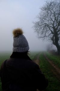 Rear view of woman standing on field in park during foggy weather