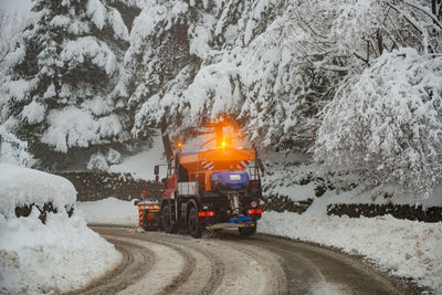 Snow covered railroad tracks by road during winter