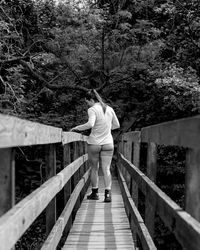 Rear view of woman walking on footbridge