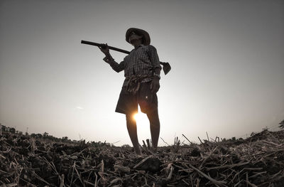 Man standing on field against clear sky during sunset