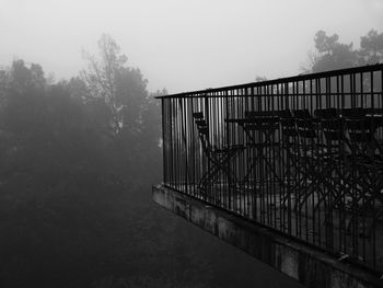 Footbridge by tree against sky