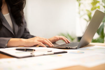 Midsection of businesswoman using laptop at office