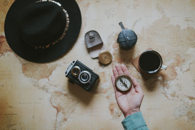 Cropped hand holding navigation compass over table