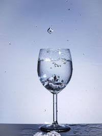 Close-up of water splashing on glass against white background