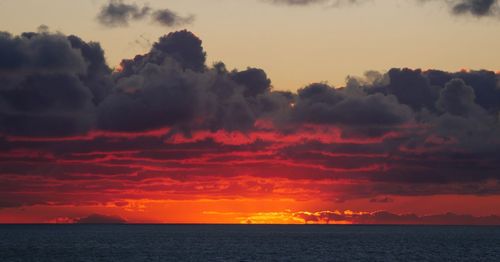 Scenic view of sea against dramatic sky during sunset