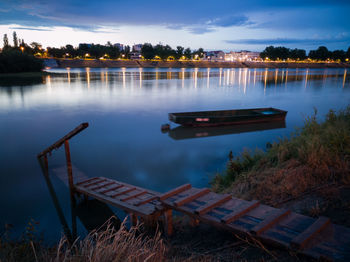 Landscape with river and moored boat during dusk with dark clouds at horizon