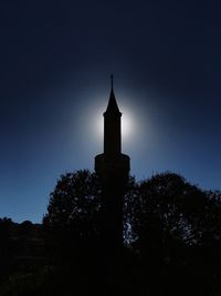 Low angle view of silhouette trees and building against sky