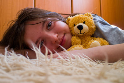 Portrait of young woman with teddy bear on bed at home