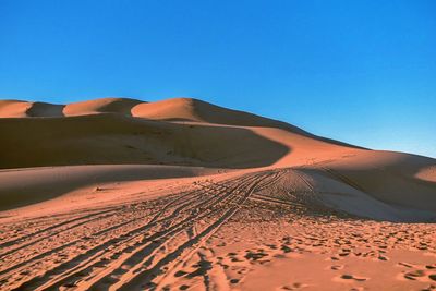 Scenic view of desert against clear blue sky