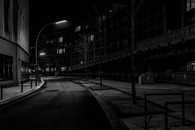 Empty road amidst buildings in city at night