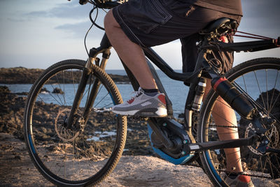 Low section of man riding bicycle by sea