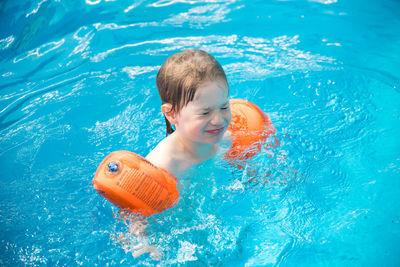 High angle view of smiling boy swimming in pool