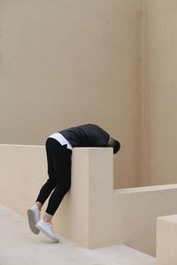 Rear view of young man sitting on wall