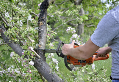 Side view of man holding bicycle against plants