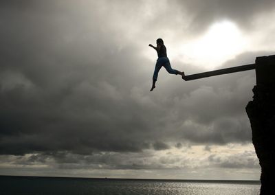 Man jumping on sea against sky