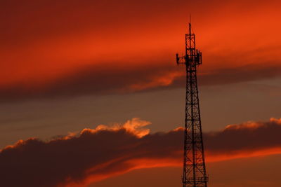 Low angle view of communications tower against orange sky