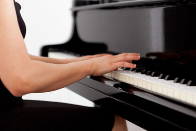 Midsection of woman playing piano at home