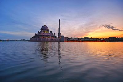 Reflection of mosque in river against sky