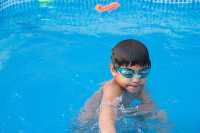 Portrait of shirtless boy swimming in pool