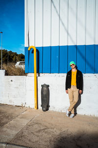 Portrait of young man standing against yellow wall