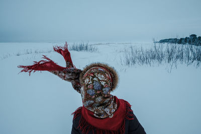 Rear view of woman wearing warm clothing standing on snow covered land