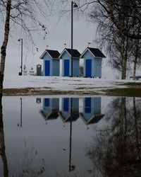 Reflection of houses in lake against sky