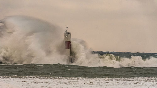 Scenic view of sea waves splashing against sky
