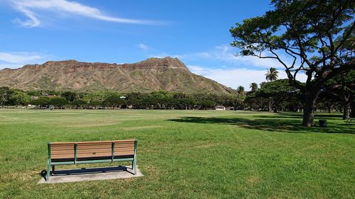 Bench in park against sky